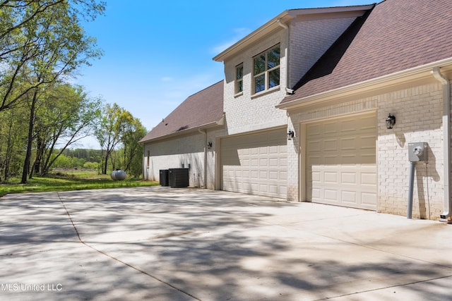 13721 Pebble Ridge Dr, Byhalia, MS 38611 - view of property exterior featuring a garage, concrete driveway, a shingled roof, brick siding, and central AC