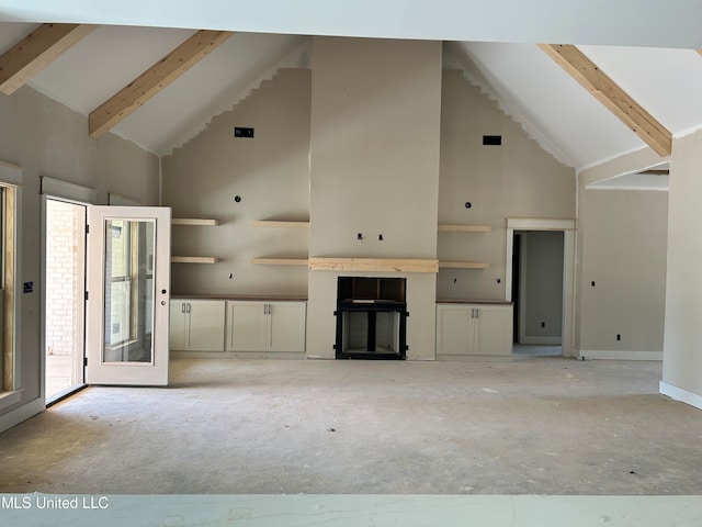 unfurnished living room with beamed ceiling, a wealth of natural light, and high vaulted ceiling