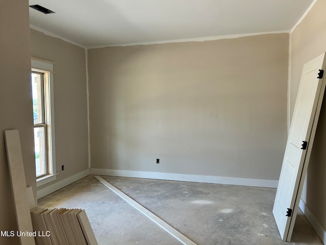 spare room featuring visible vents, baseboards, concrete floors, and ornamental molding