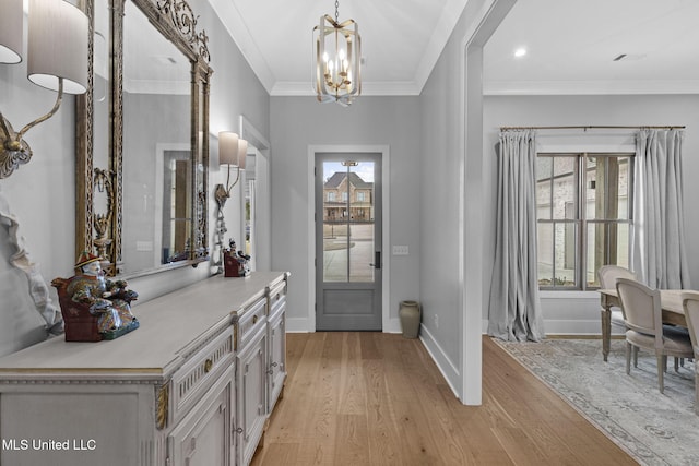 foyer with crown molding, a notable chandelier, and light wood-type flooring