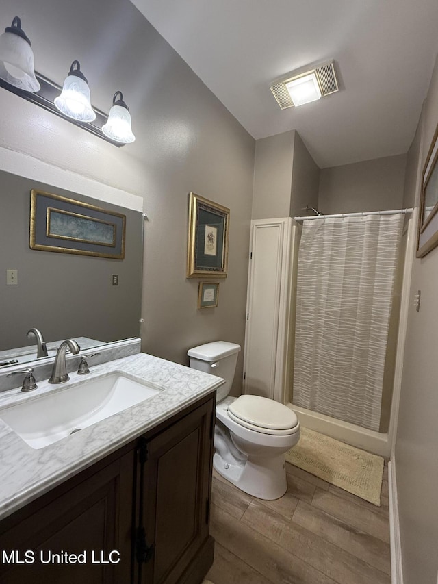 518 Main St, Natchez, MS 39120 - bathroom with wood finish floors, vanity, toilet, and a shower with shower curtain