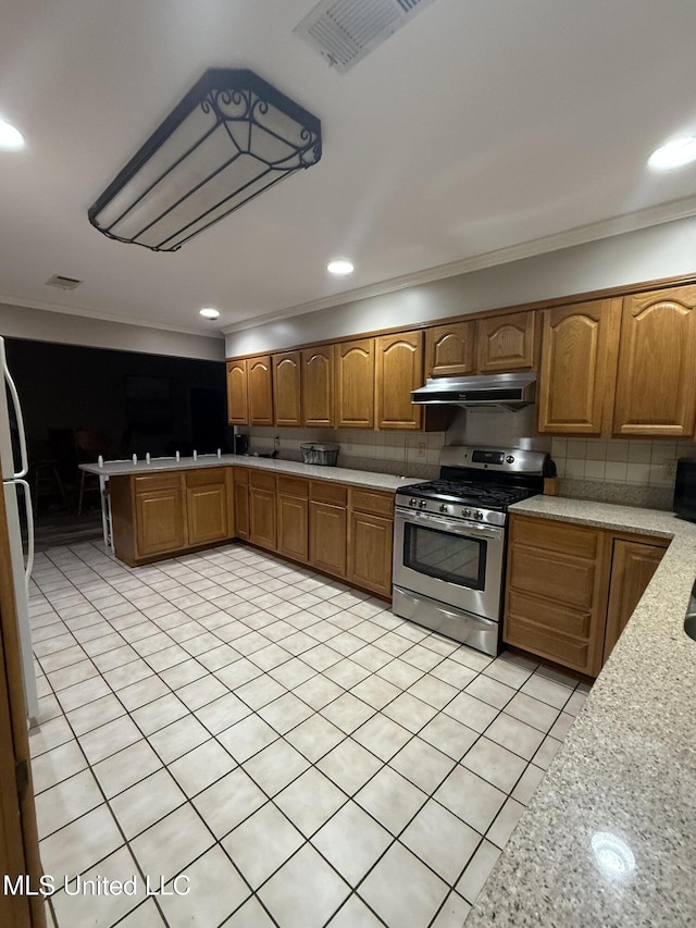 518 Main St, Natchez, MS 39120 - kitchen with stainless steel range with gas cooktop, crown molding, under cabinet range hood, tasteful backsplash, and brown cabinetry