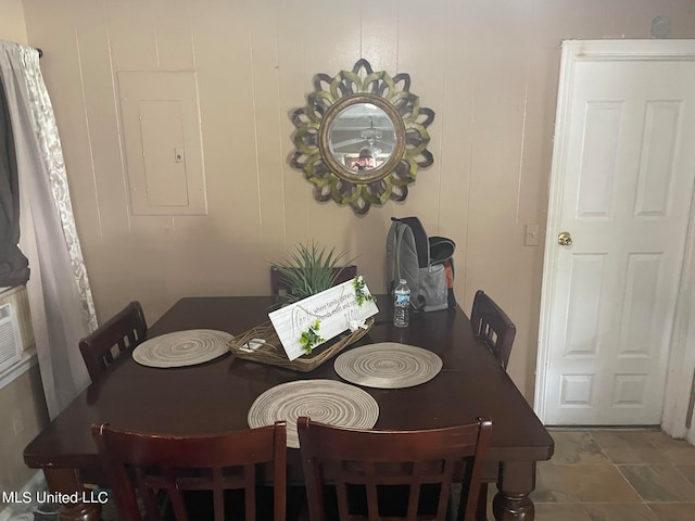 tiled dining area featuring electric panel and wooden walls