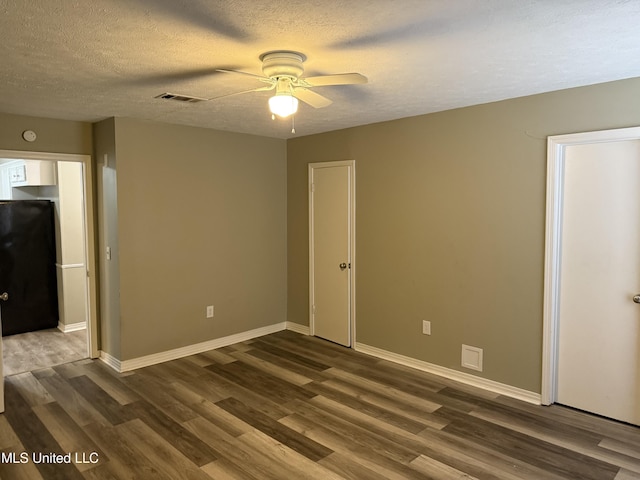 spare room with a textured ceiling, dark hardwood / wood-style flooring, and ceiling fan