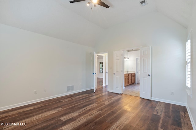unfurnished bedroom with lofted ceiling, dark wood-type flooring, baseboards, ensuite bathroom, and a ceiling fan