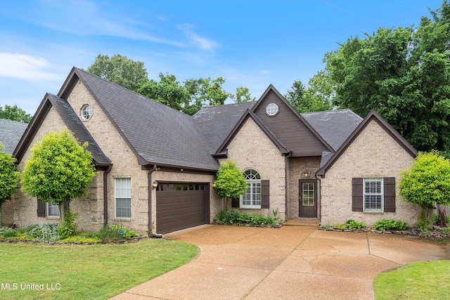 french country home with driveway, brick siding, a garage, and a shingled roof