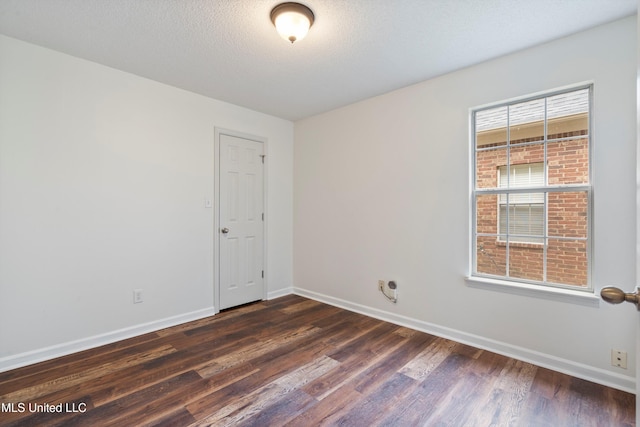 unfurnished room with dark wood finished floors, baseboards, and a textured ceiling