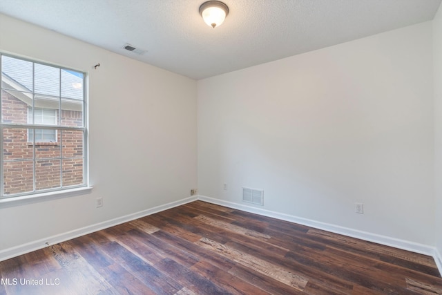 spare room with dark wood-type flooring, baseboards, and a textured ceiling