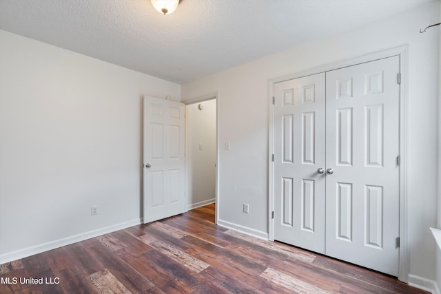 unfurnished bedroom with wood finished floors, a closet, baseboards, and a textured ceiling