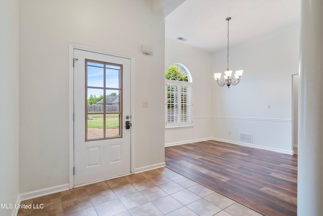 foyer with healthy amount of natural light, a chandelier, wood finished floors, and baseboards