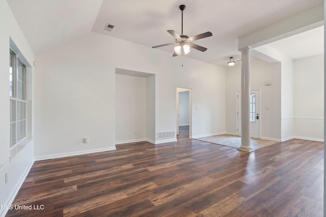 empty room featuring decorative columns, vaulted ceiling, dark wood-style floors, a ceiling fan, and baseboards