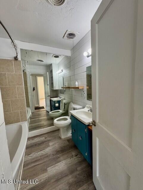 106 Laurel Ave, Natchez, MS 39120 - bathroom featuring vanity, wood finished floors, toilet, tile walls, and a textured ceiling