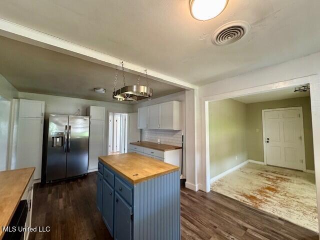 106 Laurel Ave, Natchez, MS 39120 - kitchen featuring wood counters, stainless steel fridge, blue cabinetry, dark wood-type flooring, and baseboards