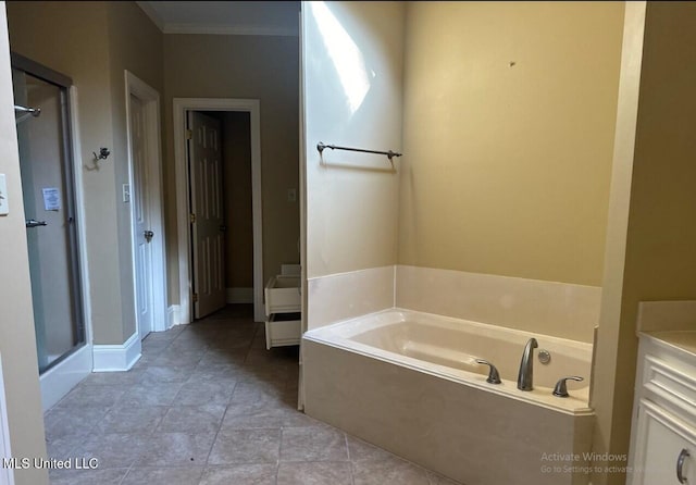 bathroom with baseboards, a stall shower, crown molding, a bath, and tile patterned floors