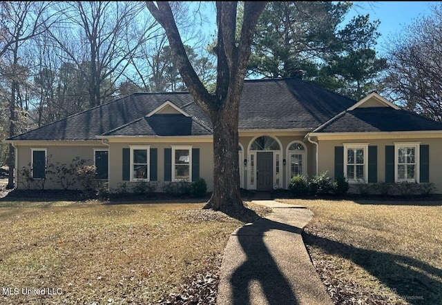 ranch-style home with stucco siding, a shingled roof, and a front yard