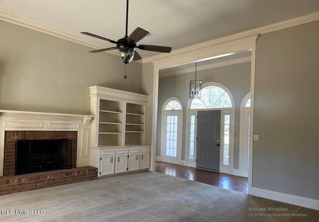 carpeted foyer with baseboards, a high ceiling, ornamental molding, and a fireplace