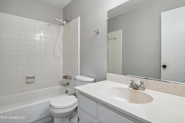 full bathroom featuring tiled shower / bath, vanity, and toilet