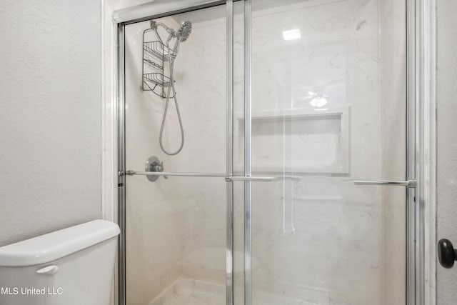 bathroom featuring toilet and an enclosed shower