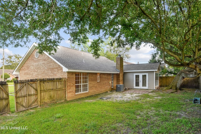 back of property featuring cooling unit, french doors, and a lawn