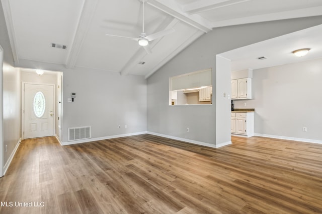 unfurnished living room with vaulted ceiling with beams, light wood-type flooring, and ceiling fan