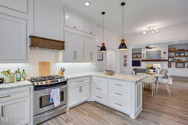 kitchen with pendant lighting, stainless steel range with gas cooktop, white cabinetry, and light hardwood / wood-style floors