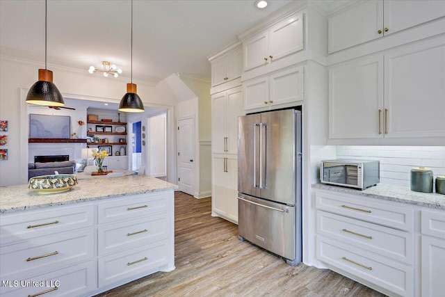 kitchen featuring decorative light fixtures, light stone countertops, white cabinetry, and appliances with stainless steel finishes