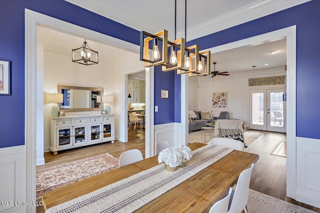 dining area featuring hardwood / wood-style floors, ceiling fan, ornamental molding, and french doors