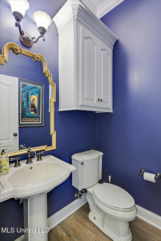 bathroom with toilet, ornamental molding, and wood-type flooring