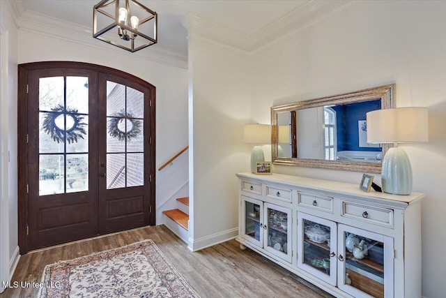 entryway featuring hardwood / wood-style flooring, an inviting chandelier, crown molding, and french doors