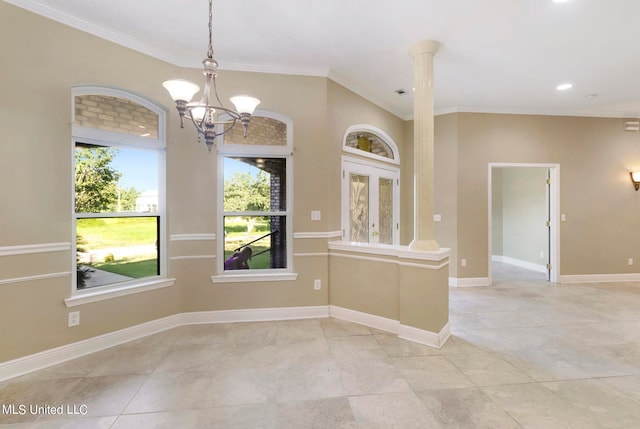 spare room with ornate columns, crown molding, and a notable chandelier