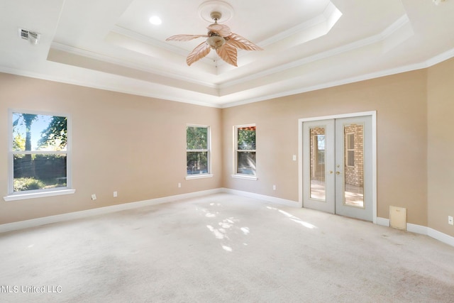 carpeted spare room with a tray ceiling, ceiling fan, french doors, and crown molding