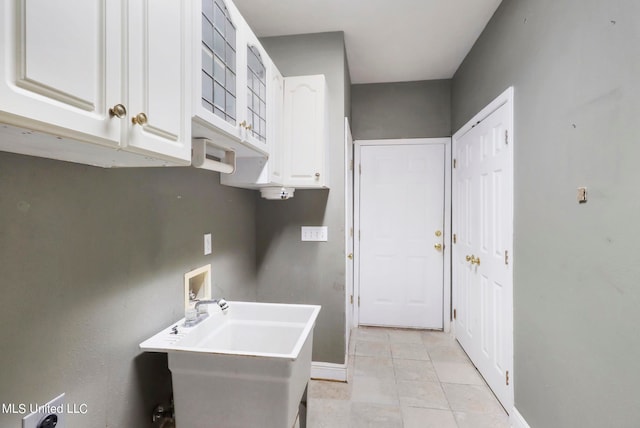 laundry room with cabinets, light tile patterned floors, hookup for a washing machine, and sink