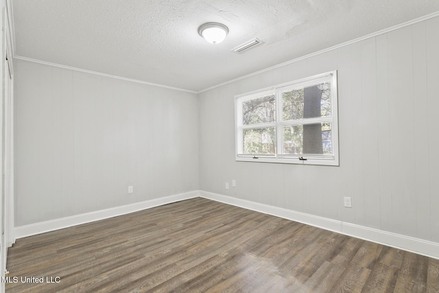 empty room with a textured ceiling, dark hardwood / wood-style floors, and ornamental molding