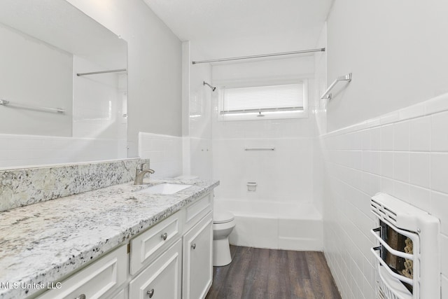 full bathroom with hardwood / wood-style floors, vanity, radiator, toilet, and tile walls