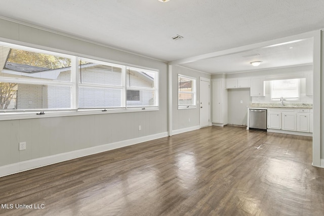 unfurnished living room with a textured ceiling, dark hardwood / wood-style flooring, ornamental molding, and sink