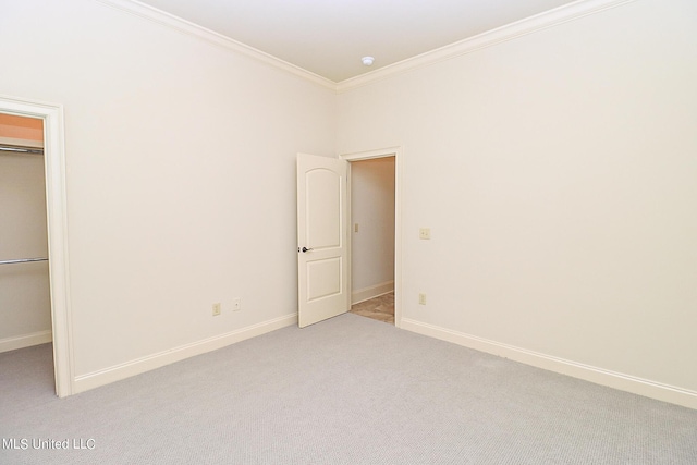 unfurnished bedroom with ornamental molding, a spacious closet, light carpet, and a closet