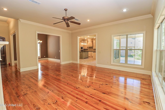 unfurnished living room with ceiling fan with notable chandelier, ornamental molding, and light wood-type flooring