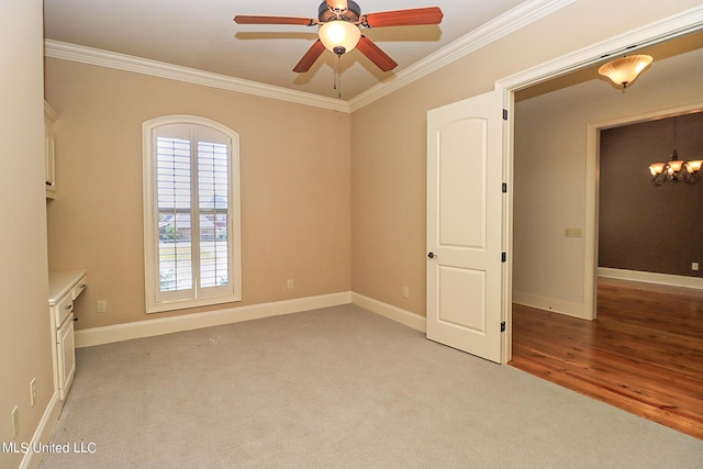 carpeted spare room with crown molding and ceiling fan with notable chandelier