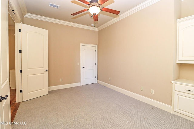 unfurnished bedroom with ceiling fan, light colored carpet, and crown molding