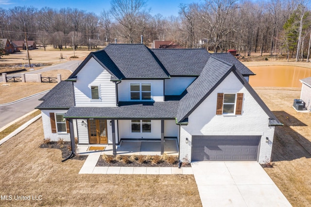 view of front of home with brick siding, roof with shingles, driveway, and an attached garage