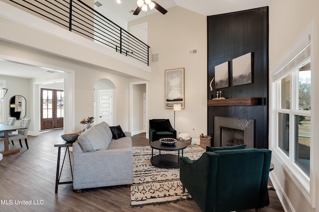 living room featuring high vaulted ceiling, a healthy amount of sunlight, wood-type flooring, and a large fireplace