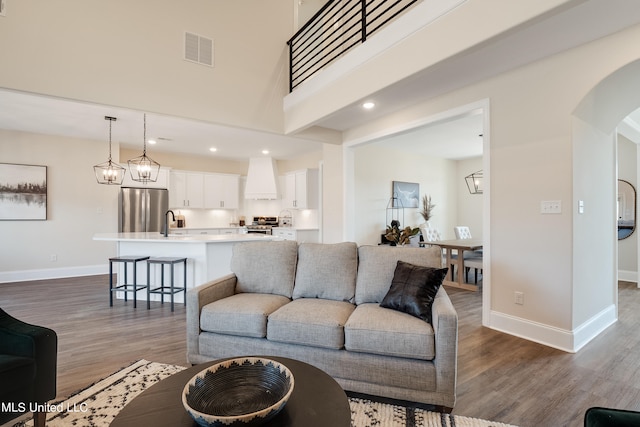 living room with hardwood / wood-style flooring, sink, and a high ceiling