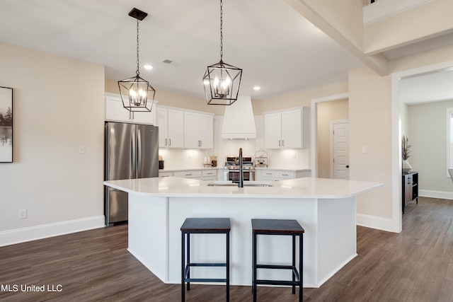 kitchen featuring custom exhaust hood, a center island with sink, appliances with stainless steel finishes, white cabinetry, and dark hardwood / wood-style floors