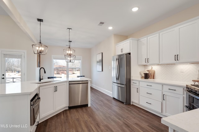 kitchen featuring a sink, appliances with stainless steel finishes, visible vents, light countertops, and dark wood finished floors