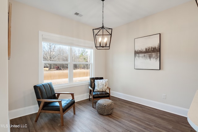 sitting room featuring dark wood-type flooring and a chandelier