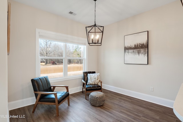living area with baseboards, a chandelier, and dark wood finished floors
