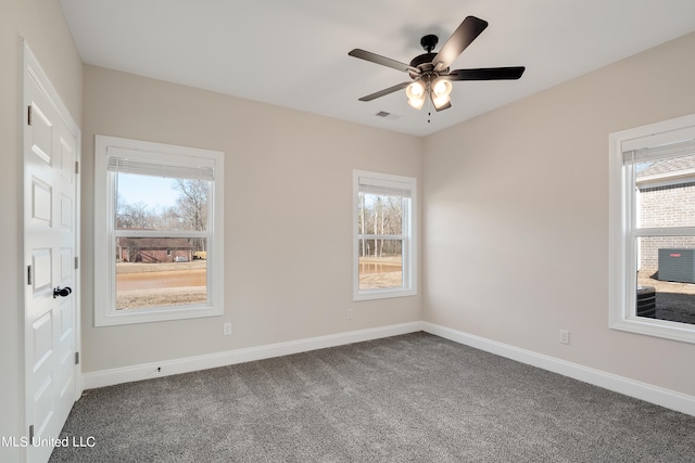 spare room with a ceiling fan, visible vents, dark colored carpet, and baseboards