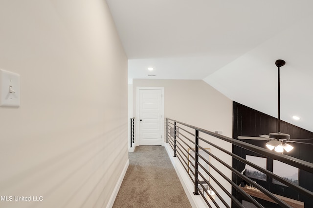 corridor featuring wood walls, carpet, and vaulted ceiling