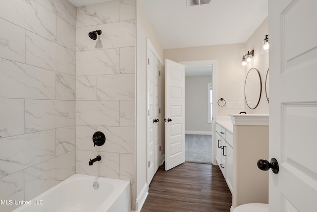 full bathroom featuring tiled shower / bath, vanity, wood-type flooring, and toilet