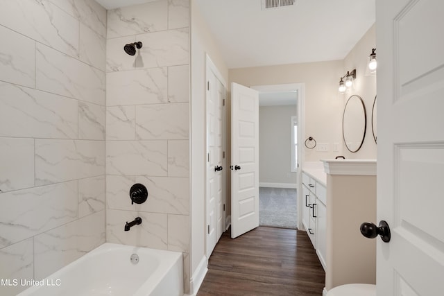 bathroom featuring tub / shower combination, wood finished floors, vanity, and baseboards
